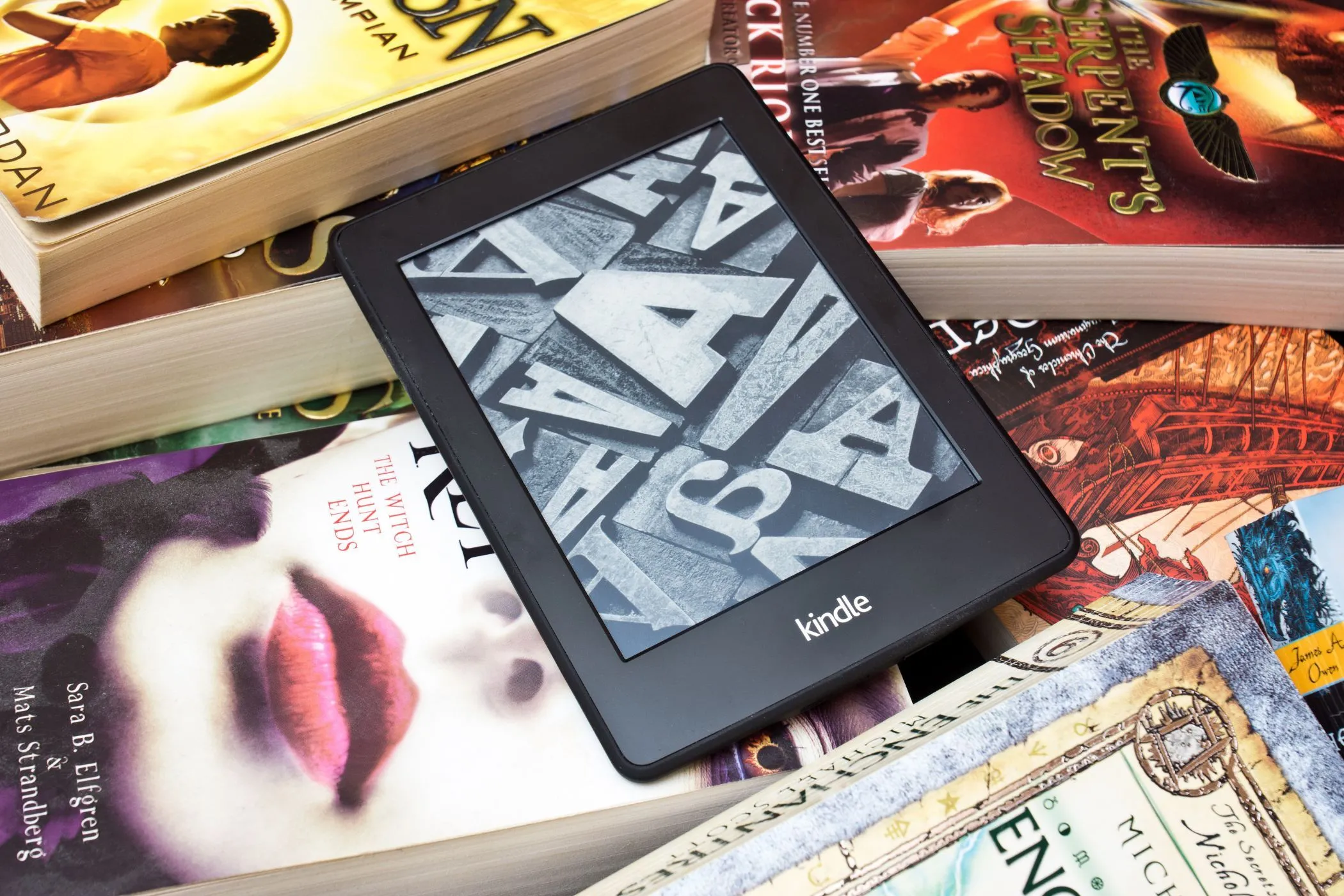Thiết bị đọc sách Kindle đặt trên chồng sách vật lý, minh họa cho thư viện eBook của Amazon