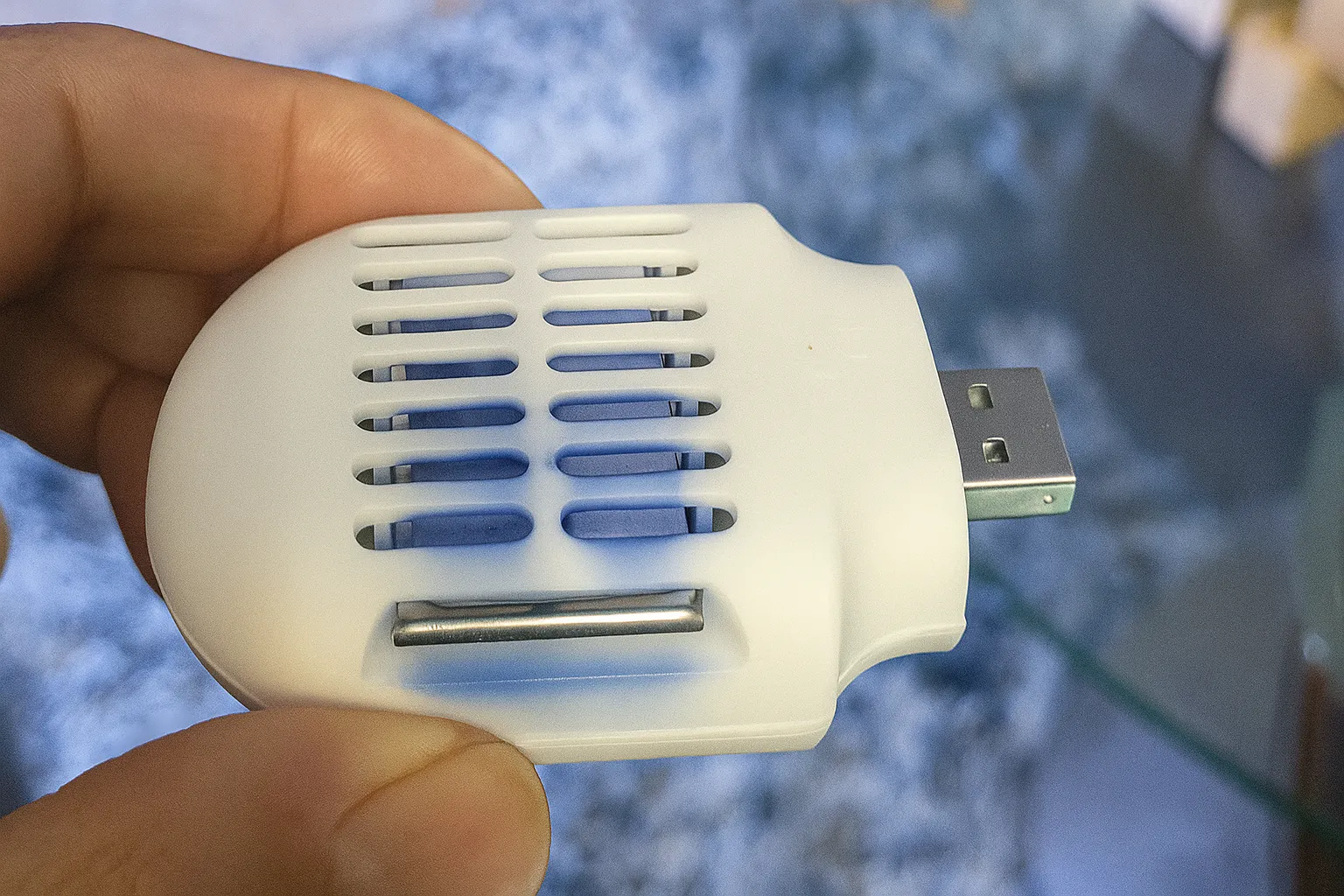 Thiết bị đuổi muỗi USB nhỏ gọn màu trắng được cầm trên tay